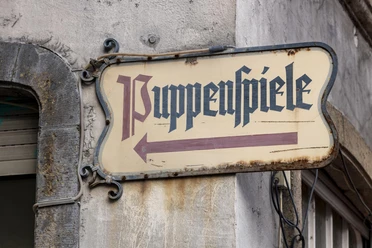 Hänneschen Theater Sign with "Puppenspiele", attached to a building wall.