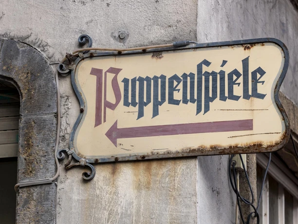 Hänneschen Theater Schild mit "Puppenspiele", an einer Gebäudewand angebracht.