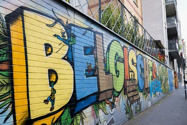 Street Art im Belgischen Viertel Auf einer langen, farbenfrohen Mauer sind große Graffiti-Buchstaben zusehen, die verspielte Details zeigen.