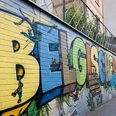 Street Art im Belgischen Viertel Auf einer langen, farbenfrohen Mauer sind große Graffiti-Buchstaben zusehen, die verspielte Details zeigen.