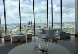 Firmenfeier_KölnSKY Blick aus Panoramafenster auf die Kölner Skyline mit Dom, Fluss und Wolkenhimmel.</p>View from the panoramic window of the Cologne skyline with cathedral, river and cloudy sky.</p> <p