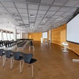 Conference room 1-3 Ein moderner Konferenzraum mit leeren Stuhlreihen und zwei großen Bildschirmen.</p>A modern conference room with empty rows of chairs and two large screens.</p> <p