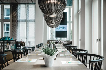 4711 Duftseminar Modern restaurant with long tables, stylish black chairs and elegant ceiling lamps.</p> <p