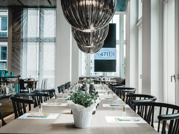 4711 Duftseminar Modern restaurant with long tables, stylish black chairs and elegant ceiling lamps.</p> <p