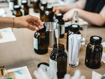 4711 Fragrance seminar 3 Person greift zu Flasche mit Pipette in Parfümkurs, umgeben von Duftessenzen und Teststreifen.</p>Person reaches for bottle with pipette in perfume course, surrounded by fragrance essences and test strips.</p> <p