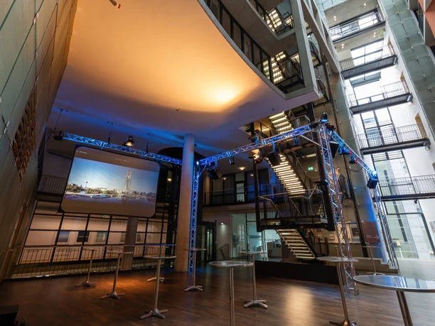 Saal-Foyer Moderner Innenraum mit Bühne, beleuchtet in Blau, und rollstuhlgerechten Zugängen.</p>