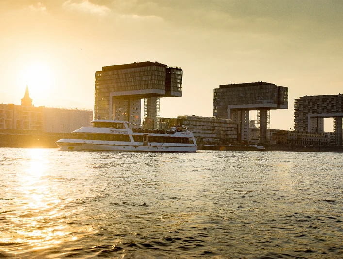 MS_Jan_v_Werth Sonnenuntergang über dem Rhein mit vorbeifahrendem Schiff und Kranhäusern im Hintergrund.</p>