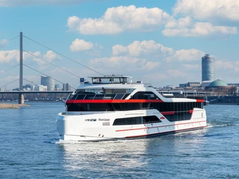Rhein Galaxie Das Luxus-Ausflugsschiff "RheinGalaxie" fährt auf dem Rhein, mit Stadt und Brücke im Hintergrund.The luxury excursion boat "RheinGalaxie" sails on the Rhine, with the city and bridge in the background.