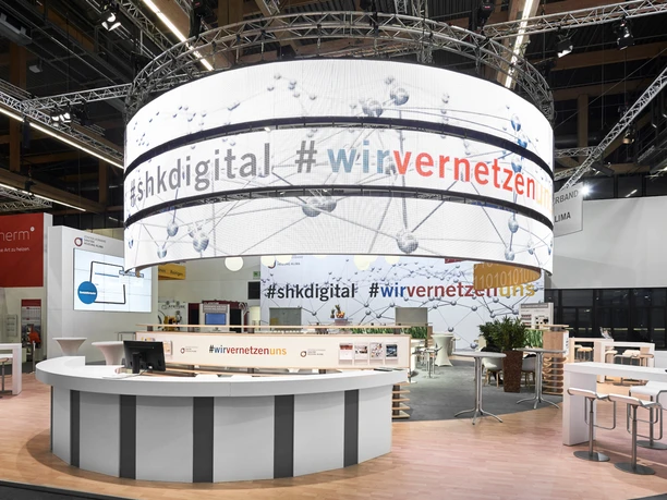 SHK-Messestand Exhibition stand with large, round LED screen, displays digital hashtags, modern presentation.</p> <p