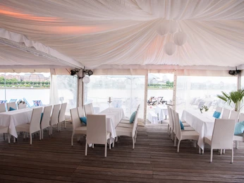 km 689 Cologne Beach Club, DomBlick Lounge Elegantes Zelt mit weißen Tischen und Stühlen, Blick auf Flusslandschaft im Hintergrund.</p>Elegant tent with white tables and chairs, view of the river landscape in the background.</p> <p