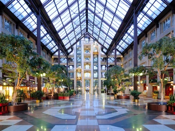 Hotelhalle / Glasgalerie Das Bild zeigt ein modernes, lichtdurchflutetes Atrium mit Glasdach und üppigen Pflanzen.The picture shows a modern, light-flooded atrium with a glass roof and lush plants.