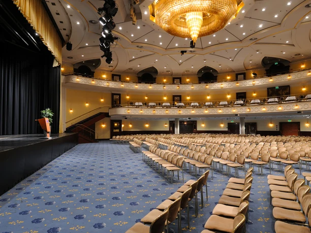 Saal Maritim Ein eleganter, leerer Theatersaal mit goldenen Details und einem großen Kronleuchter.