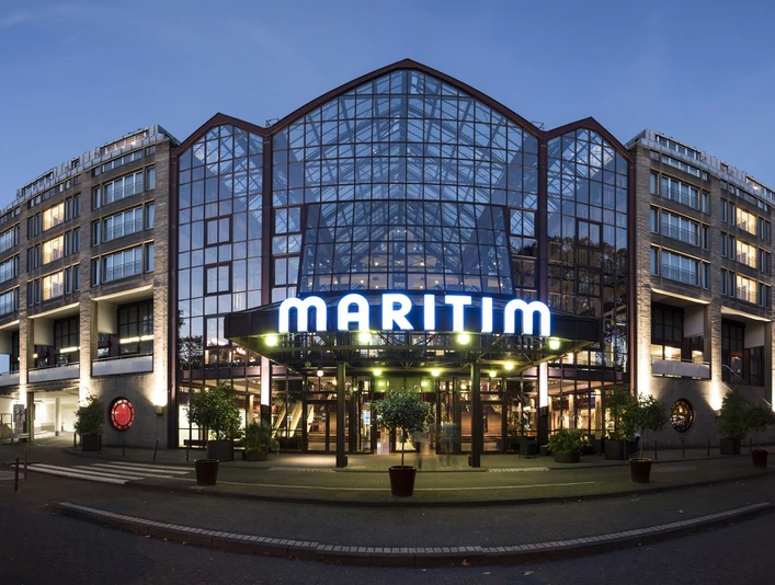 Maritim Hotel Köln Das Maritim Hotel mit Glasfassade und beleuchtetem Eingang in der Abenddämmerung.</p>The Maritim Hotel with its glass façade and illuminated entrance at dusk.</p> <p