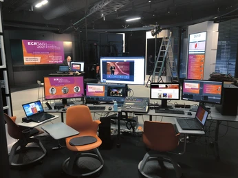Streaming Studio Moderner Regieraum mit mehreren Computermonitoren und einem großen Präsentationsbildschirm.</p>Modern control room with several computer monitors and a large presentation screen.</p> <p