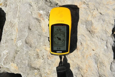 GPS.jpg Leuchtend gelbes, tragbares GPS-Gerät liegt auf einem Felsen in der Sonne. Bildschirm zeigt Kompass.</p>