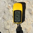 GPS.jpg Leuchtend gelbes, tragbares GPS-Gerät liegt auf einem Felsen in der Sonne. Bildschirm zeigt Kompass.</p>Bright yellow, portable GPS device lying on a rock in the sun. Screen shows compass.</p>