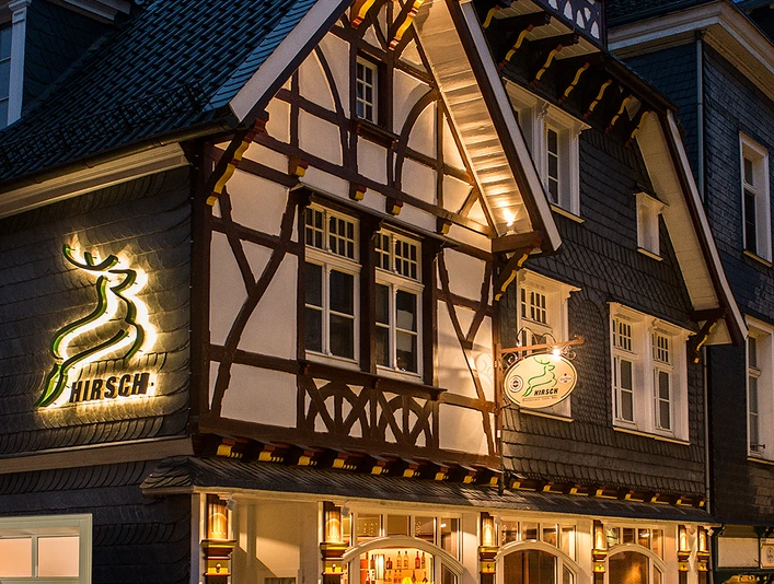 Hirsch Restaurant_Fassade.jpg Fachwerkhaus mit beleuchteter Fassade, Restaurant "Hirsch", traditionelle Elemente, abends aufgenommen.