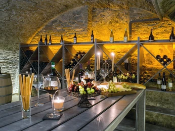 Hirsch Restaurant_Weinverkostung im Gewölbekeller.jpg Ein stimmungsvoller Gewölbekeller mit gestapelten Weinflaschen, einer gedeckten Tafel und Kerzen.