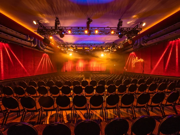 A7R00450.jpg Illuminated theater hall with empty rows of chairs and red velvet background; stage in the light.</p> <p