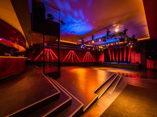 A7R00661.jpg An empty concert stage with red and blue stage lighting and a black floor.