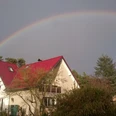 DSC_0232 Herzog.JPG Zweistöckiges Haus mit rotem Dach im Vordergrund, beeindruckender Regenbogen am Himmel darüber.