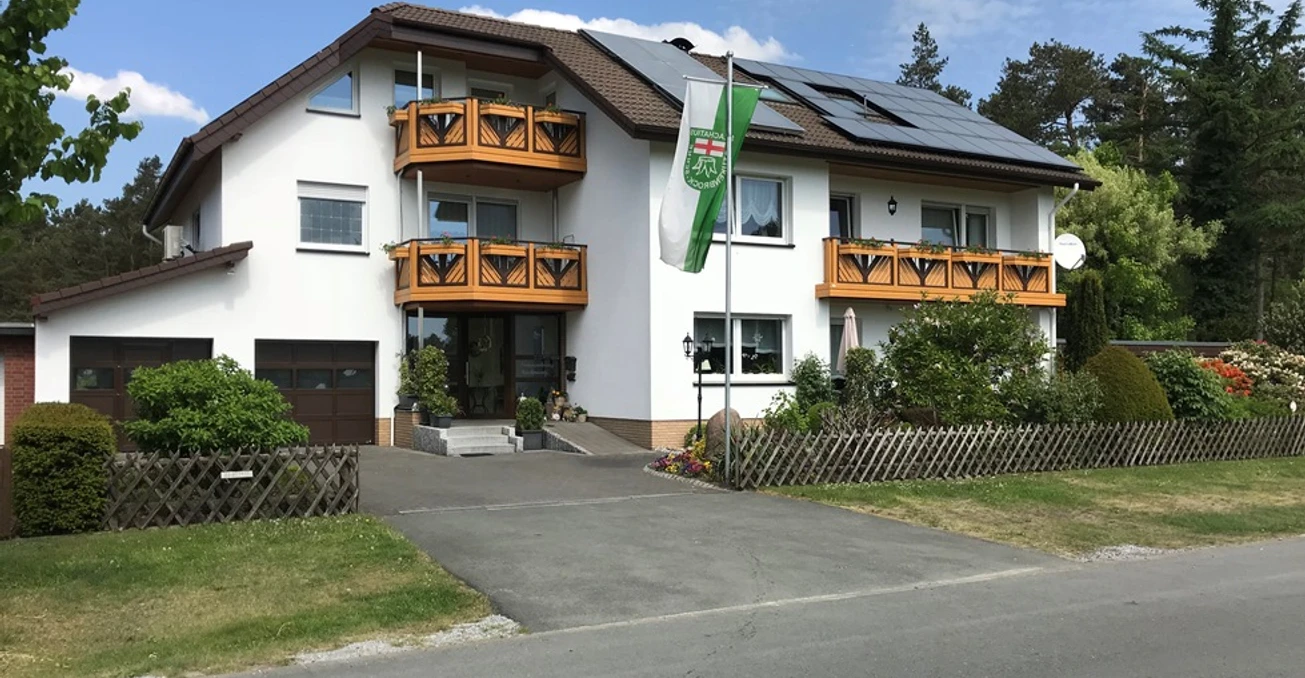 Ferienwohnung Hachmann 09.05.2018 bearb.© Hachmann.jpg Großes, modernes Haus mit weißen Wänden und Holzbalkonen, umgeben von gepflegtem Garten.