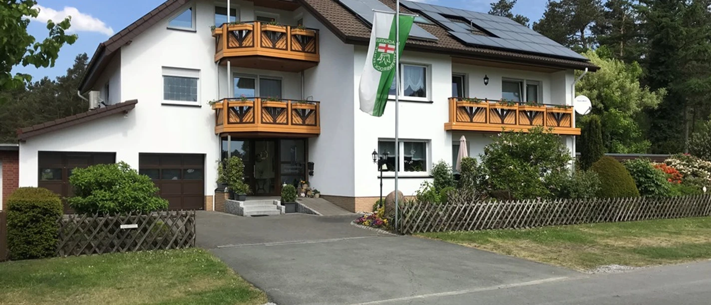Ferienwohnung Hachmann 09.05.2018 bearb.© Hachmann.jpg Großes, modernes Haus mit weißen Wänden und Holzbalkonen, umgeben von gepflegtem Garten.