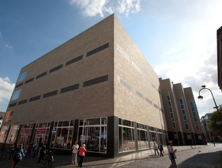 Außenansicht Wallraf ohne Banner_ (c) by C.Quester Kopie.jpg Ein modernes Museum mit sandfarbenen Fassaden, großen Glasfenstern und Fußgängern davor.Exterior view of the Wallraf-Richartz Museum