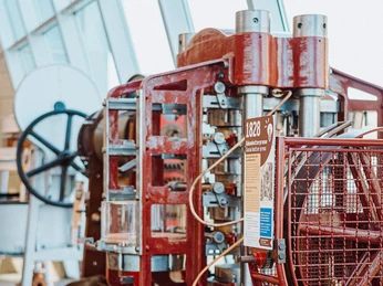Führung 3 Historische Druckmaschine im Technischen Museum, rot lackiert, mit Infotafel zur Jahrgangsangabe.Historical printing press in the Technical Museum, painted red, with vintage information board.