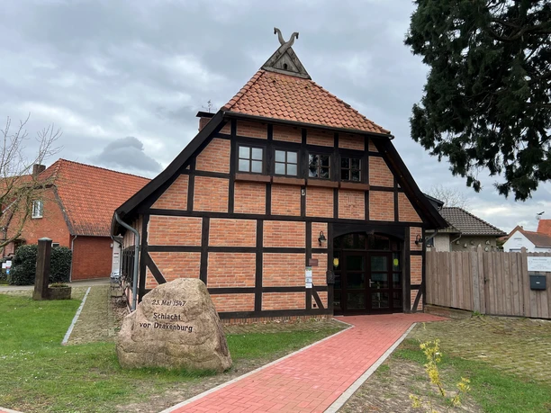 Ole Schüne Drakenburg Fachwerkgebäude in Drakenburg mit rotem Ziegeldach, umgeben von Bäumen und Wiesen, historisches Flair.