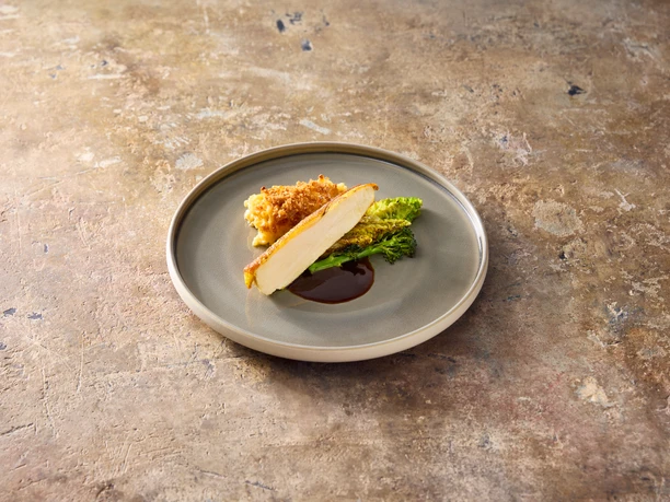 Food2 Fried chicken breast fillet with a crispy crust, served on a savoy cabbage leaf and sauce on a gray plate.