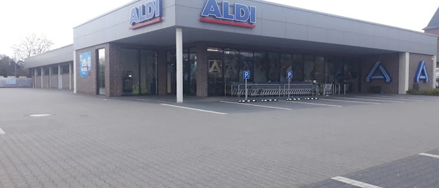 2023-03-19.jpg Das Bild zeigt eine ALDI-Filiale mit weitläufigem Parkplatz, Einkaufswagenbereich und moderner Fassade.
