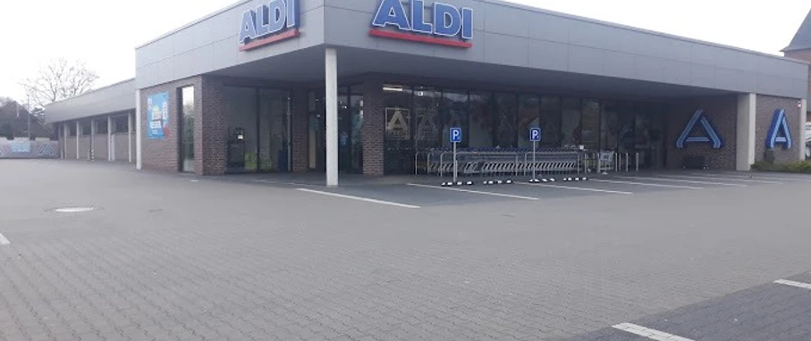 2023-03-19.jpg Das Bild zeigt eine ALDI-Filiale mit weitläufigem Parkplatz, Einkaufswagenbereich und moderner Fassade.