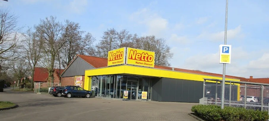 Netto_Apen_2023.jpg Außenansicht eines Netto-Markts in Apen, Parkplatz und Einkaufswagenbereich.