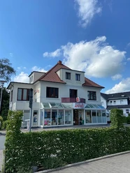 Marien-Apotheke_Augustfehn_2023.jpg Ansicht der Marien-Apotheke Augustfehn, ein zweistöckiges, weißes Gebäude mit roten Dachziegeln.