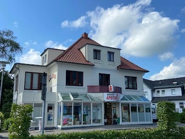Marien-Apotheke_Augustfehn_2023.jpg Ansicht der Marien-Apotheke Augustfehn, ein zweistöckiges, weißes Gebäude mit roten Dachziegeln.