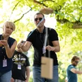 Teambuilding.jpg Teilnehmer werfen Holzstäbe bei einer freundlichen Outdoor-Veranstaltung unter einem Baum.Participants throw wooden sticks under a tree at a friendly outdoor event.
