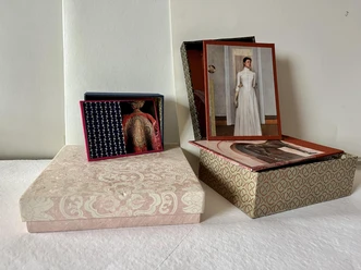 Kästchen basteln Zwei dekorative Schachteln mit traditionellen Mustern, jeweils mit geöffneten Deckeln und Kunstkarten.