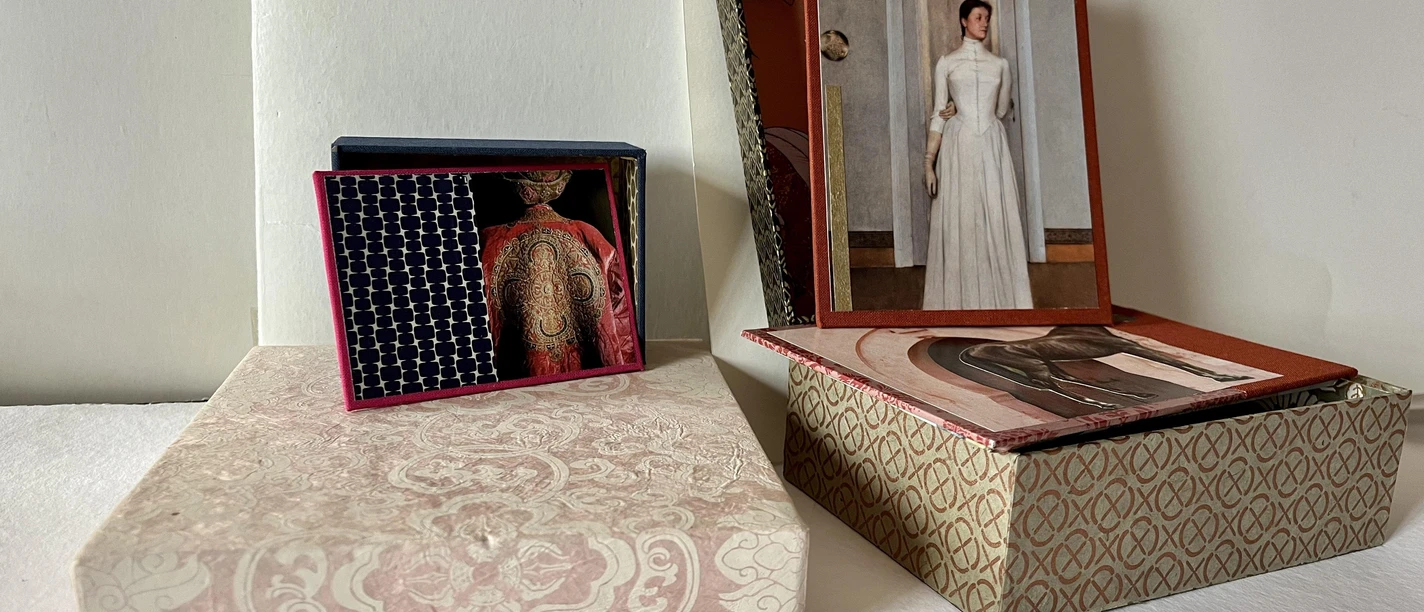 Kästchen basteln Zwei dekorative Schachteln mit traditionellen Mustern, jeweils mit geöffneten Deckeln und Kunstkarten.