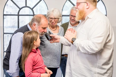 Der Geruch der Fabrik Ältere Erwachsene und ein Kind riechen an dunkler Gewürzmischung, geführt von einem Mann.