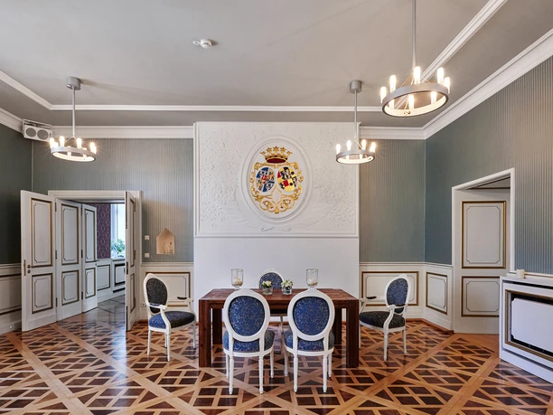 Schloß Broich, Mülheim an der Ruhr <p>Eleganter heller Raum mit Holzboden, einem Tisch und Stühlen, verziert mit einem Wappen an der Wand.</p>