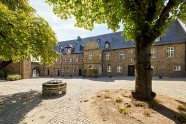 Schloß Broich, Mülheim an der Ruhr <p>Historischer Innenhof mit Brunnen, von Bäumen umgeben und mit Steinpflaster ausgelegt.</p>