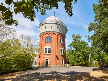Camera Obscura, Mülheim an der Ruhr Roter Backsteinturm der Camera Obscura in Mülheim, umgeben von grünen Bäumen unter blauem Himmel.