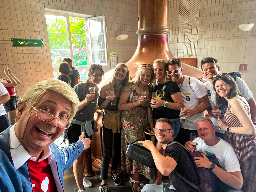 comedy-fuehring-hajo.jpg Menschen feiern lachend in einer Brauerei, umgeben von Kupferkesseln und mit Biergläsern.</p>People celebrating with laughter in a brewery, surrounded by copper kettles and with beer glasses.</p> <p