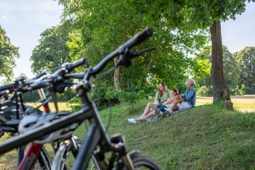 Pause am Radfernweg Hamburg-Rügen Im Schatten von Bäumen machen drei Frauen eine Pause auf ihrer Fahrradtour.