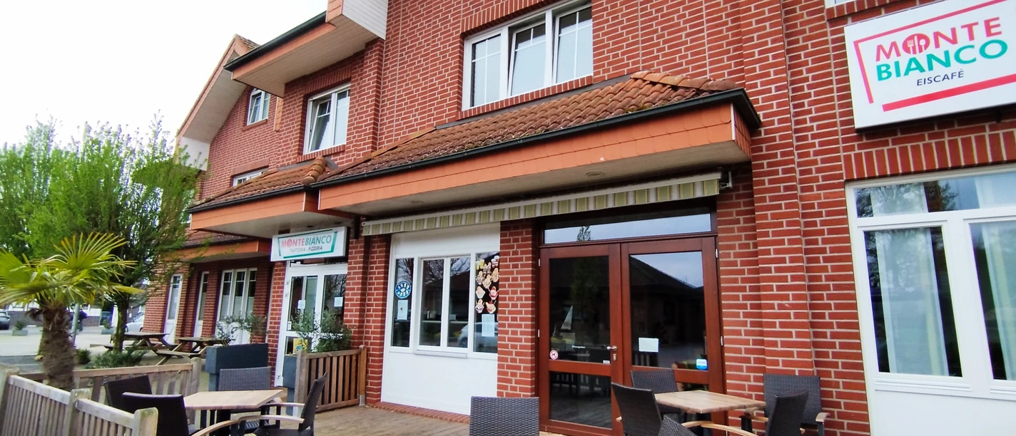 Monte-Bianco_Spelle©SG-Spelle.jpg Backsteinfassade des Monte Bianco mit Außenbereich, Sitzmöbeln und Palmen vor dem Eingang