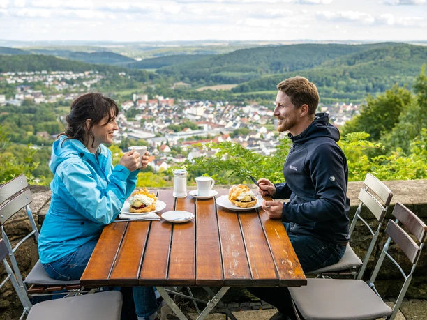 Kreis Hoexter-Sachsenklause Bad Driburg-Teutoburger-Wald-Tourismus-D-Ketz-078.jpg Eine Frau und ein Mann genießen Kaffee und Gebäck an einem Tisch mit Blick auf Bad Driburg.