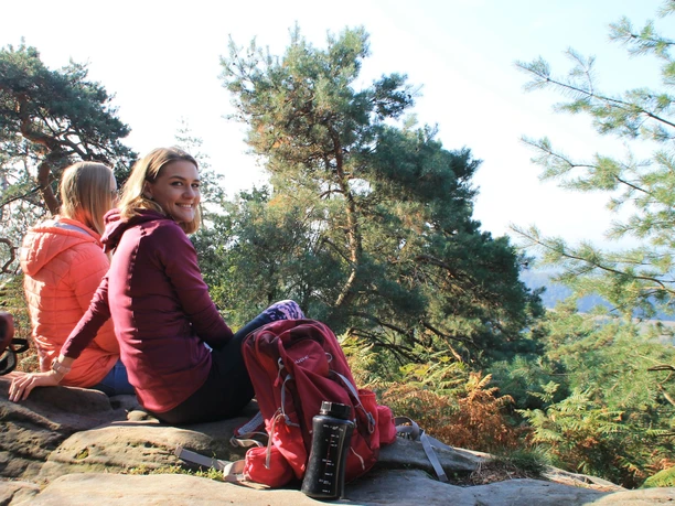 Ibbenbüren_Plisseefelsen_Stadtmarketing Ibbenbüren GmbH_SPL_2000.jpg Zwei Personen sitzen entspannt auf einem Felsen, umgeben von grünen Bäumen und genießen den Ausblick.