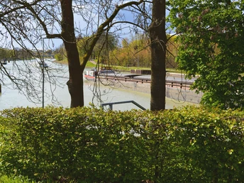 Blick durch Bäume auf eine grüne Kanalstraße mit ruhigem Rundwanderweg im Teutoburger Wald.
