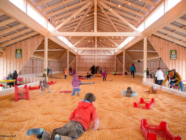 Interior view of a corn barn with children playing on dried corn kernels.